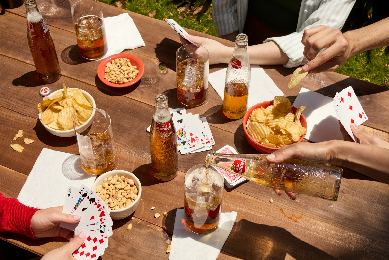 People are enjoying drinks, snacks, and cards at a picnic.